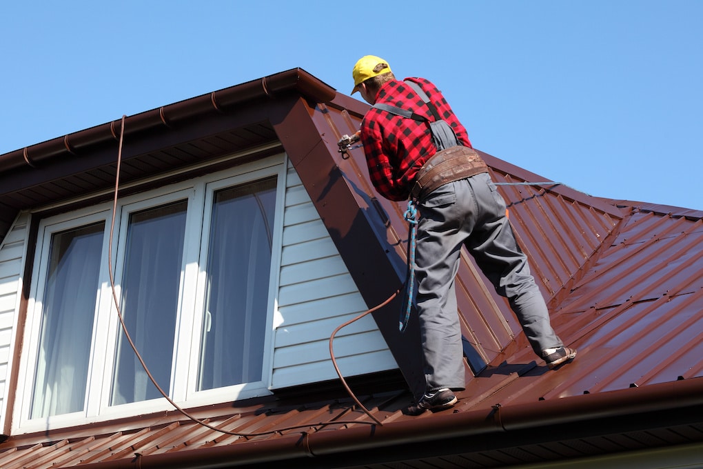 worker spraying metal roof cleaner on metal sheet roof