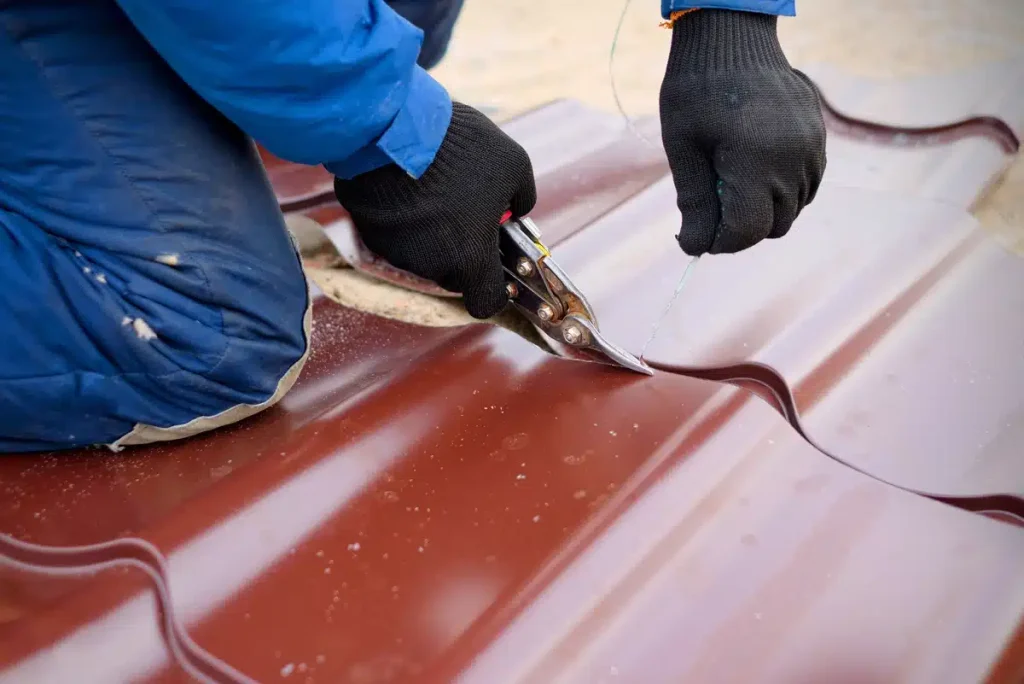 worker cutting metal roofing sheet with scissors 