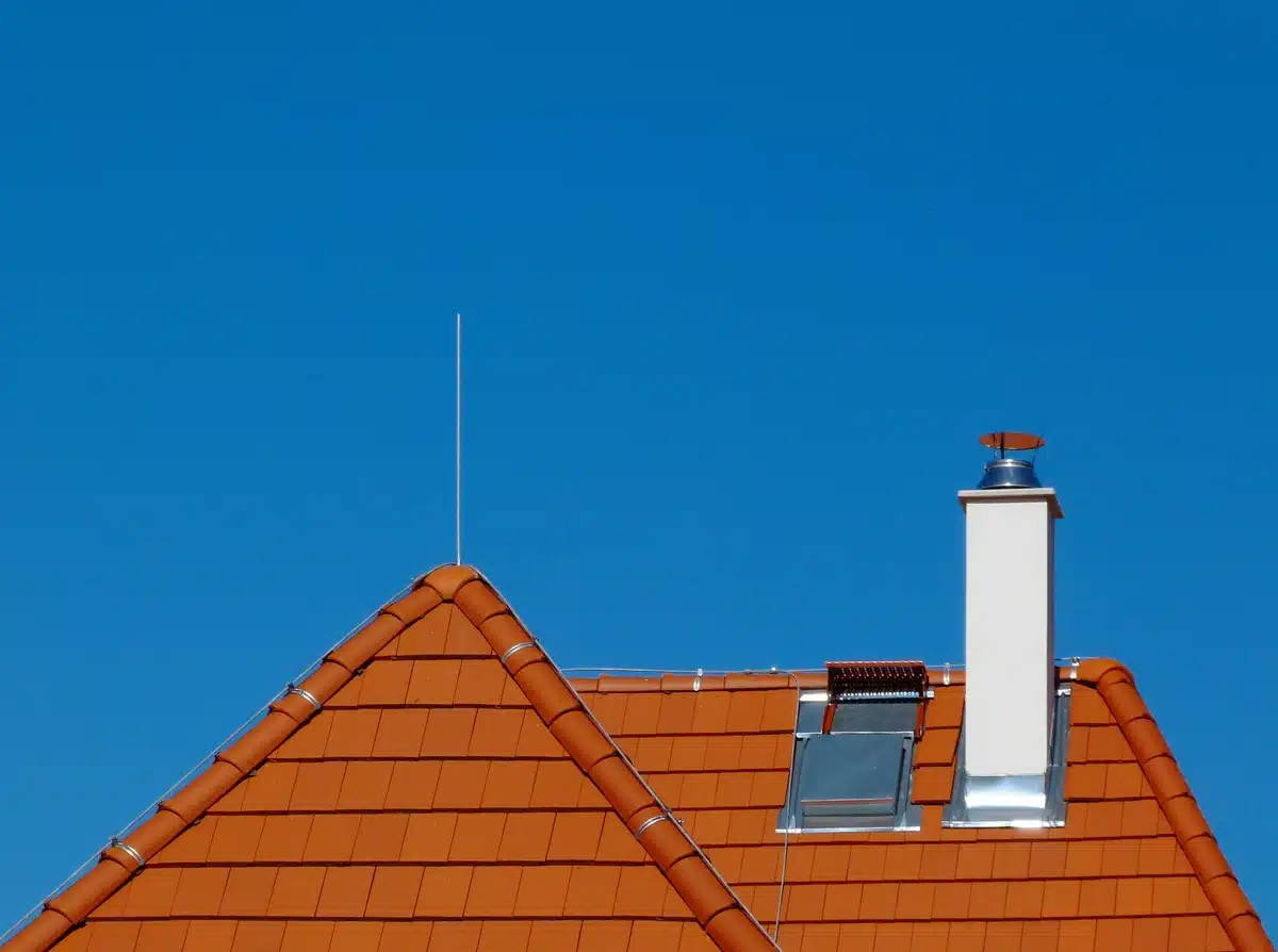 house roof against blue sky with chimney and metal flashing