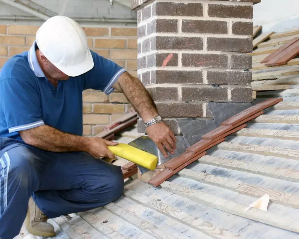 construction worker installing roof flashing on chimney