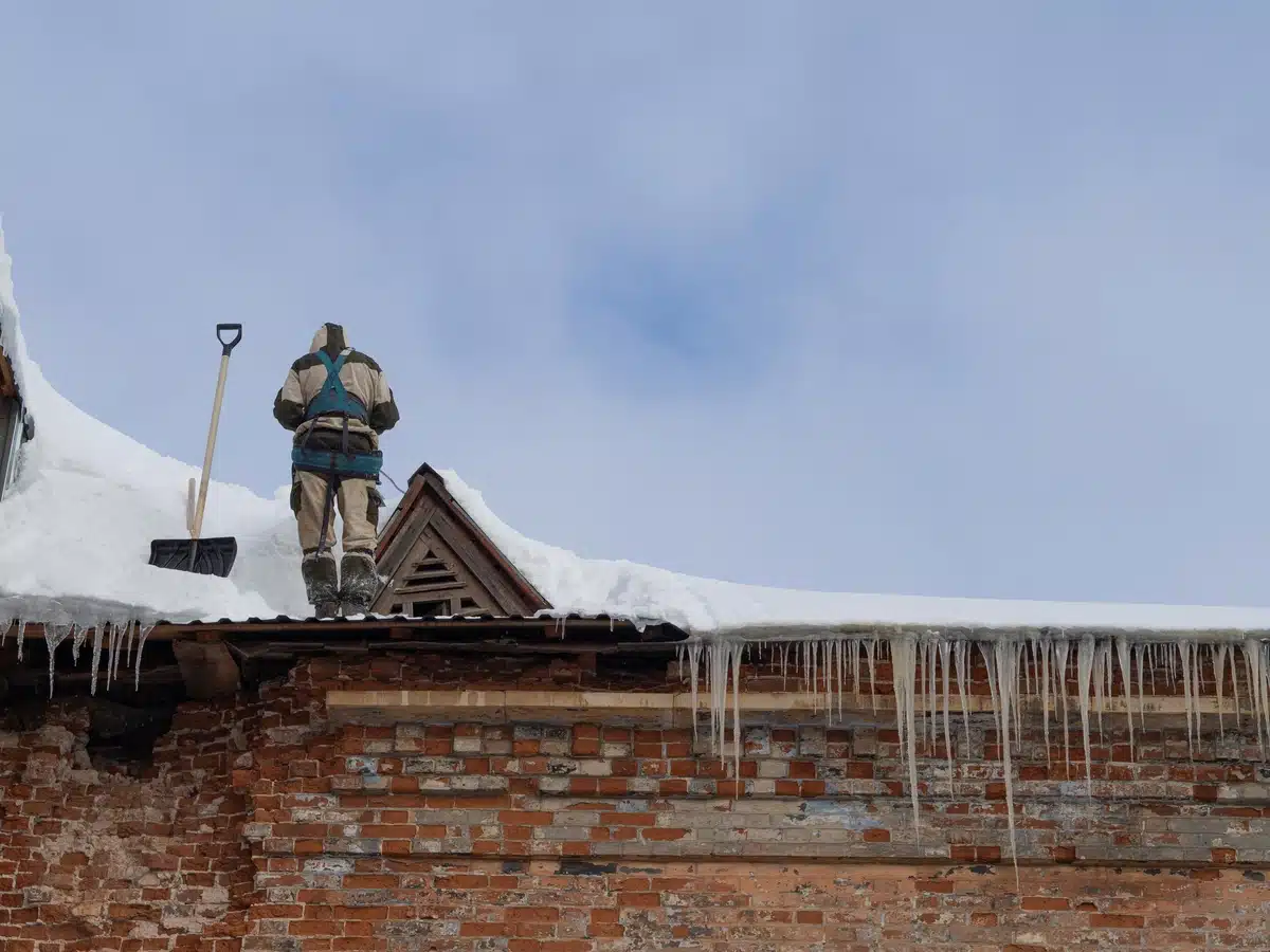 worker removing snow: roof snow removal