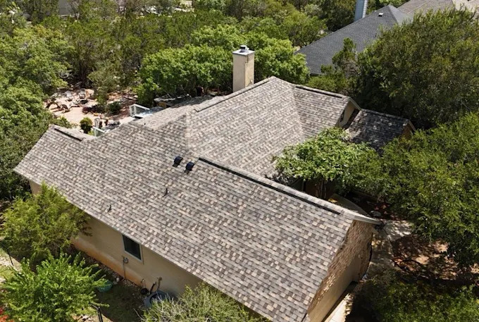 Aerial view of a light shingle roof surrounded by trees